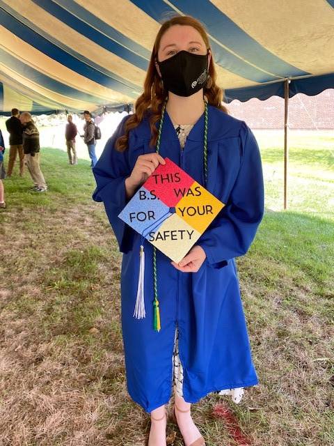 OSH graduate holding "This B.S. was for your safety" graduation cap